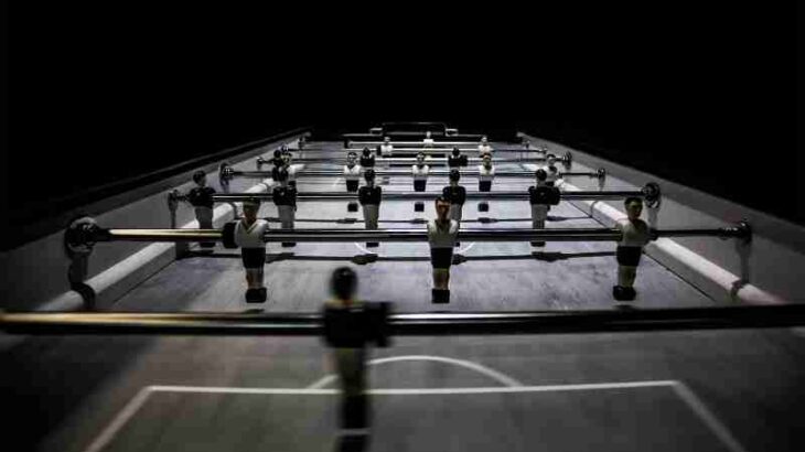 A close-up view of a foosball table under dramatic lighting, highlighting players and game dynamics., tags: und - pexel