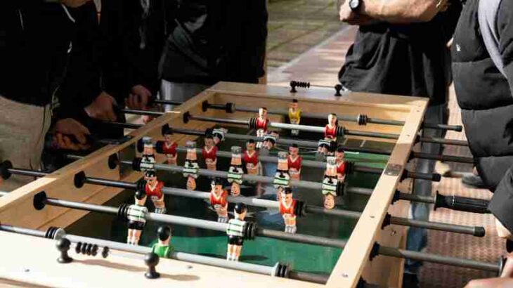 A group of people enjoying a foosball game outdoors in Portugal, captured on a sunny day., tags: disziplin - pexel